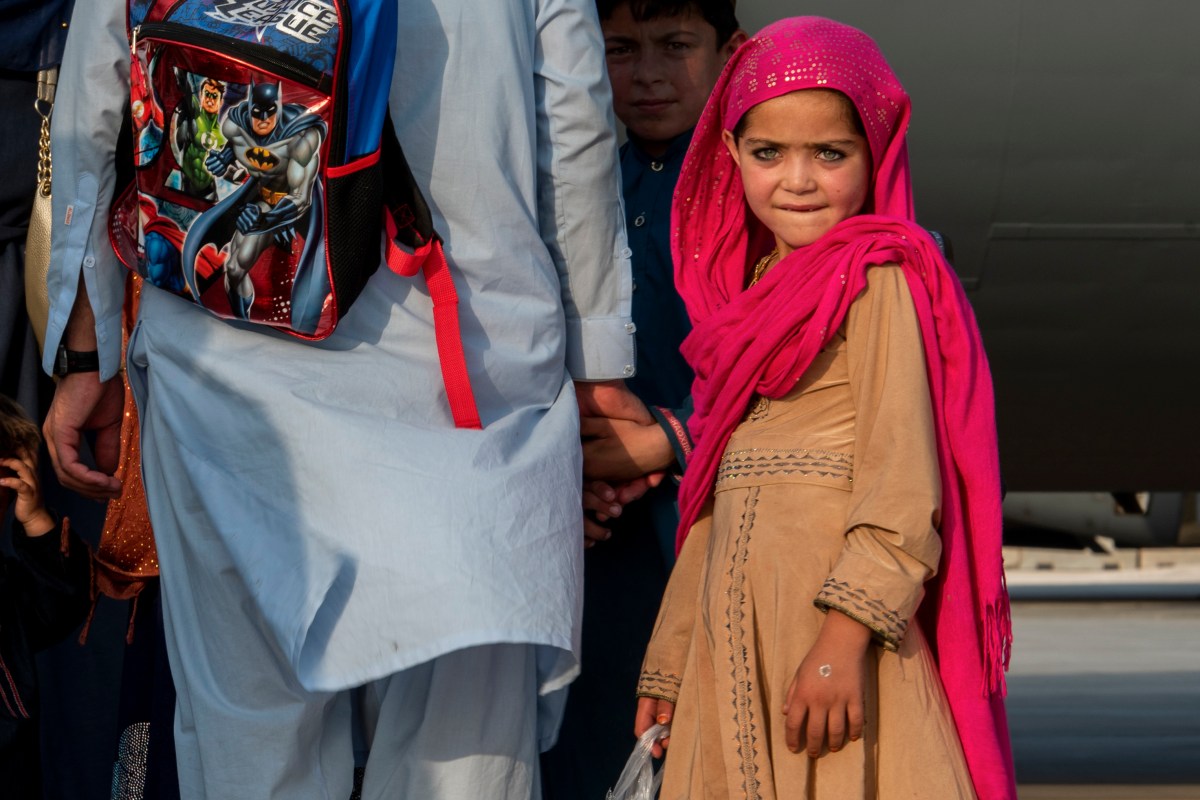 A child waits with her family to board a C-17 Globemaster lll at Al Udeid Air Base, Qatar.